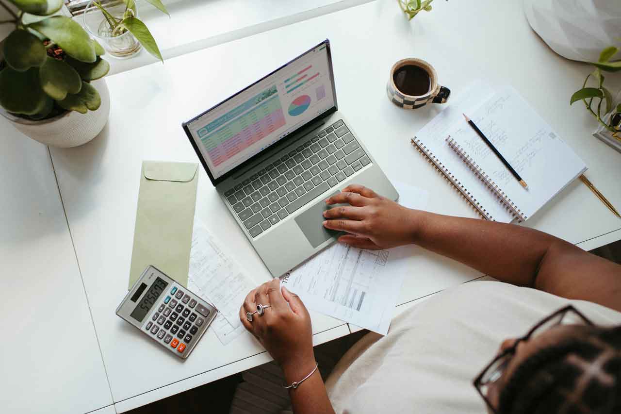 Professional reviewing financial data, documents and calculations on a laptop while evaluating private company shares.